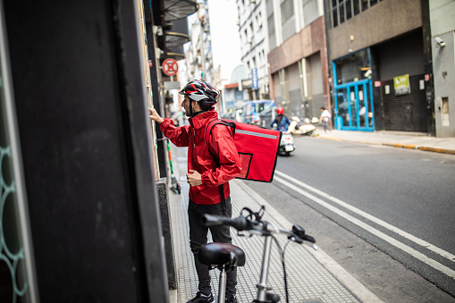 Pizza Delivery Man on bike, Ringing The Door Bell With A Large Red Bag on His back