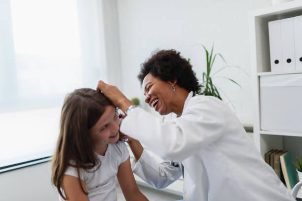 woman afro american doctor general practitioner examining ear of a ill child. ear infections. - young ears imagens e fotografias de stock