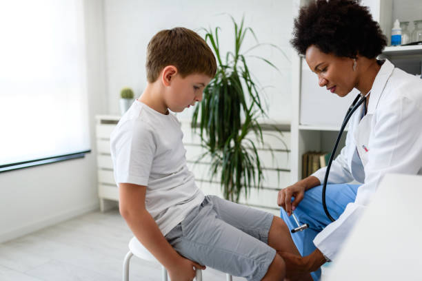 Woman African American doctor general practitioner examining child's patellar knee-jerk reflex Woman African American doctor general practitioner examining child's patellar knee-jerk reflex rubber mallet stock pictures, royalty-free photos & images