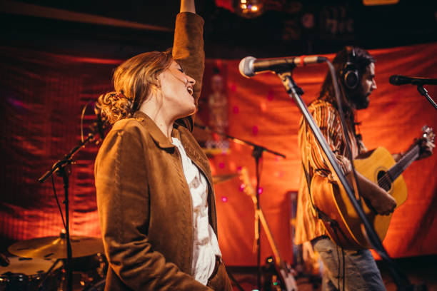 istock Young woman singing on stage with band 1193309111