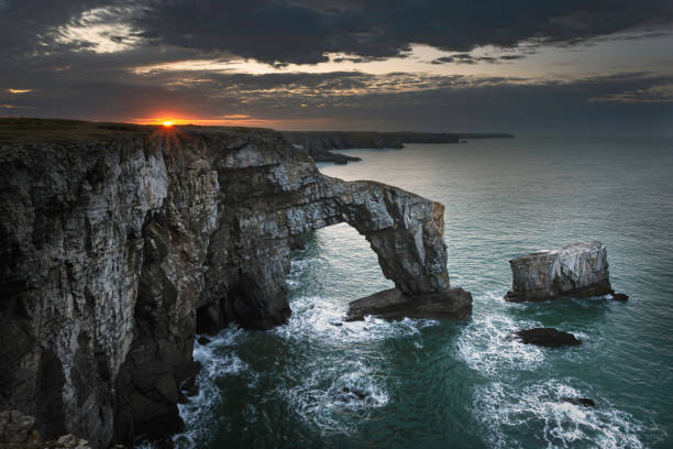 wschód słońca z dramatycznym niebem nad green bridge of wales, pembrokeshire, południowa walia, wielka brytania. - extreme terrain eroded snow landscape zdjęcia i obrazy z banku zdjęć