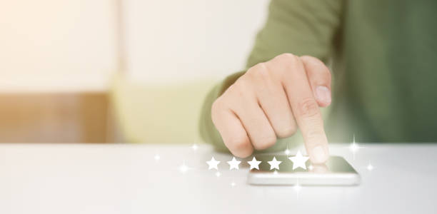 istock close up on customer man hand pressing on smartphone screen with gold five star rating feedback icon and press level excellent rank for giving best score point to review the service , technology business concept 1193310561