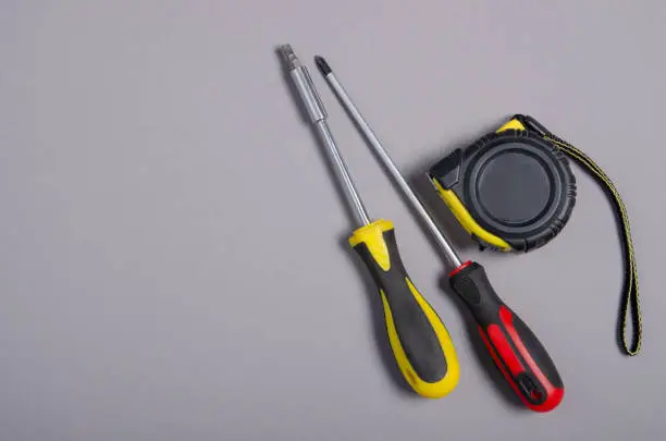 screwdrivers work tool, tape-measure on gray background, top view. Construction industry concept