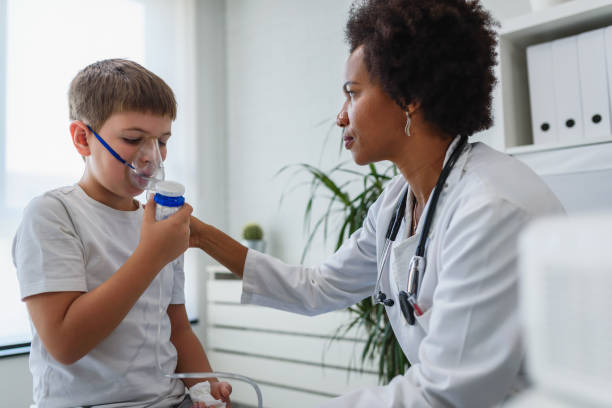 Woman African American doctor general practitioner helping child to put nebulizer inhaler face mask. Asthma treatment for children. Woman African American doctor general practitioner helping child to put nebulizer inhaler face mask. Asthma treatment for children. pediatric nebulizer mask stock pictures, royalty-free photos & images