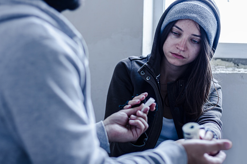 Addict young woman have meeting with  dealer in abandoned building, to buy dose of white powder cocaine. Teenage homeless girl is going to take coke, amphetamines. Drug addiction concept.