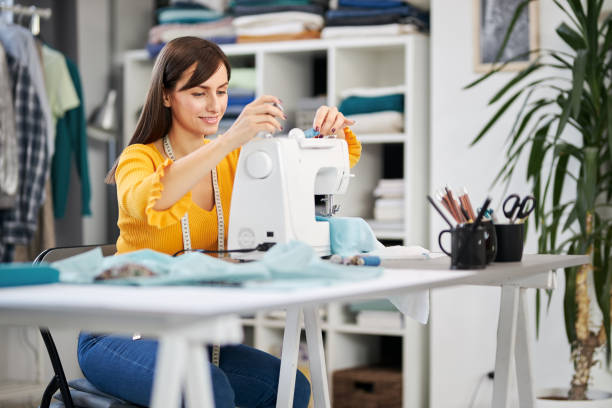 istock Dedicated seamstress sitting in her studio and inserting thread in sewing machine. 1193319971