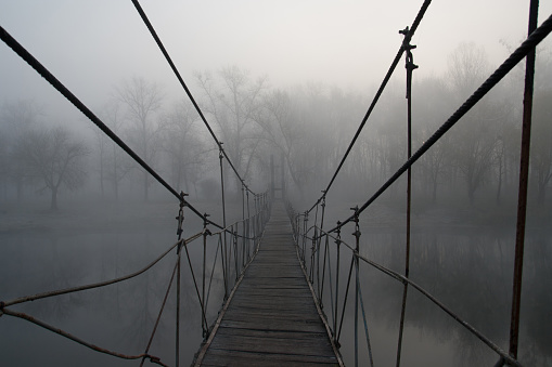 Suspension bridge over the river morning fog