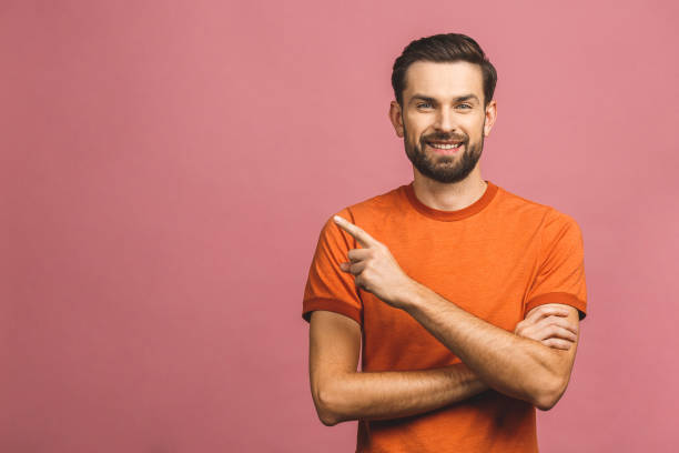 istock Look over there! Happy young handsome man in casual pointing away and smiling while standing against pink background. 1193323214