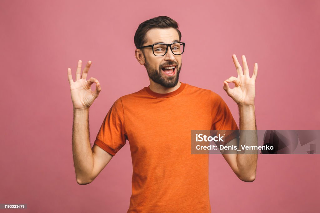 A handsome young man in casual isolated on pink background showing ok sign. Adult Stock Photo
