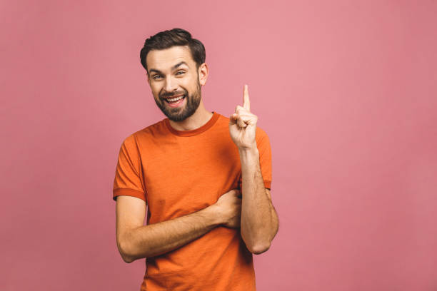 istock Look over there! Happy young handsome man in casual pointing away and smiling while standing against pink background. 1193325760