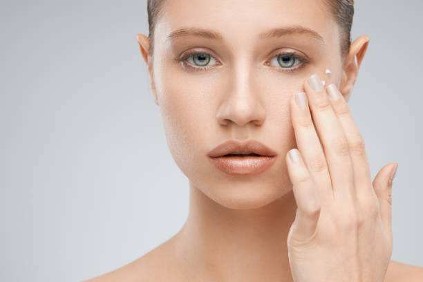 istock Beautiful caucasian brunette standing in studio and putting creme. 1193331981