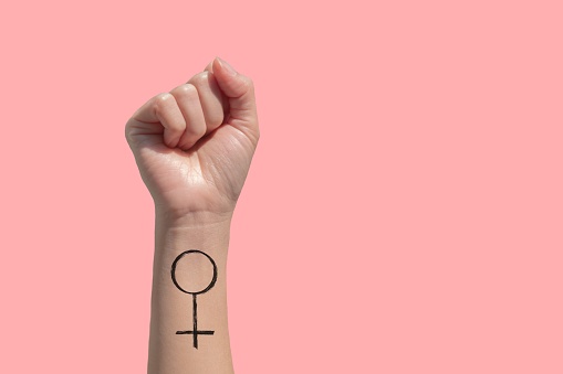 Una mano de mujer y tatuajes de signo feminista en su mano aislado sobre fondo rosa photo