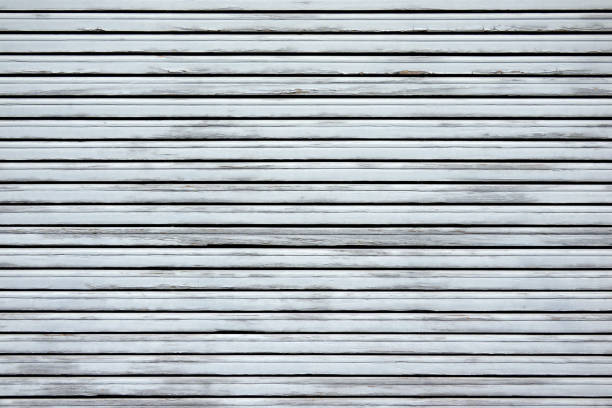 Closed weathered old light gray blind made of wood in closeup