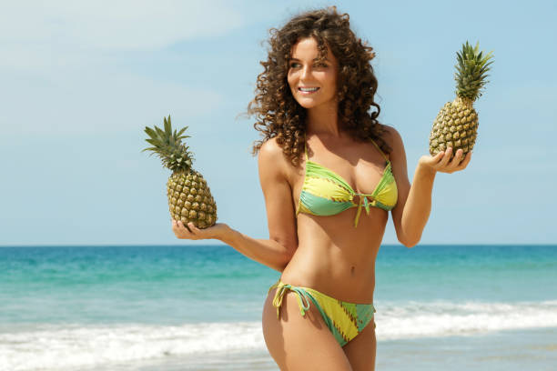 istock Woman with a pineapplel on the beach 1193344068