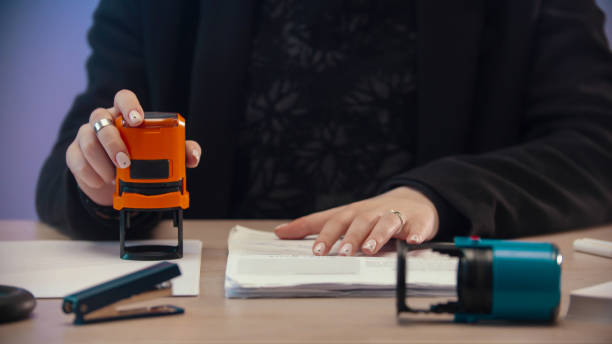 istock office concept - a woman putting a stamp on the document with a orange stamping 1193348743