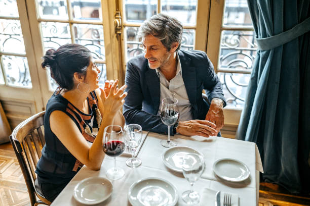 mature couple flirting in restaurant along red wine - couple restaurant day south america imagens e fotografias de stock