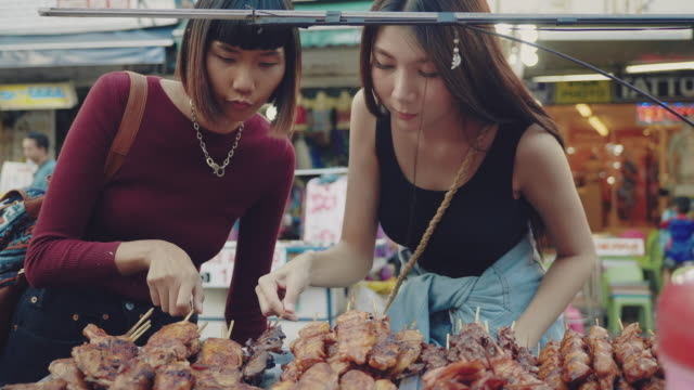 Two Young Women Enjoying Street Food in Khao San Road.