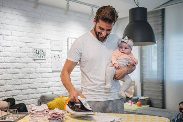istock Smiling father caring for the baby while ironing at home 1193357101