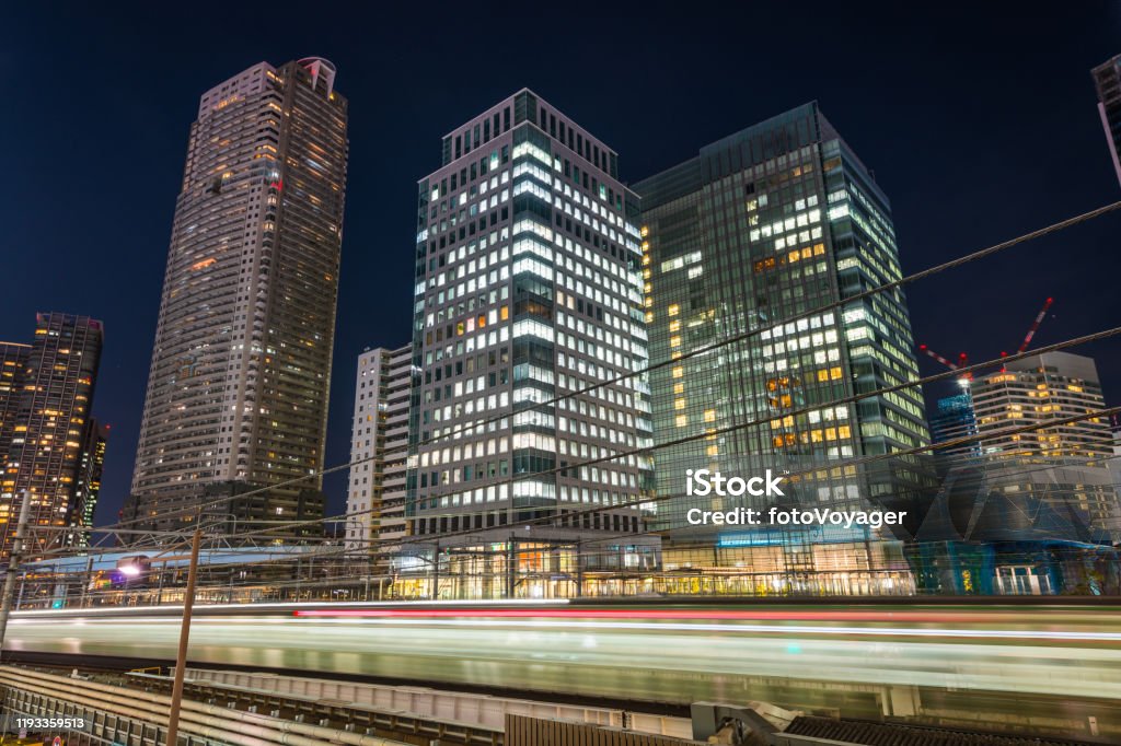 Tokyo train zooming past downtown skyscrapers illuminated at night Japan The illuminated skyscrapers of Shiodome overlooking the zooming commuter trains of Hamamatsucho station, Tokyo, Japan. Asia Stock Photo