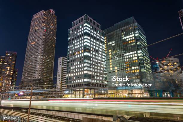 Tokyo Train Zooming Past Downtown Skyscrapers Illuminated At Night Japan Stock Photo - Download Image Now
