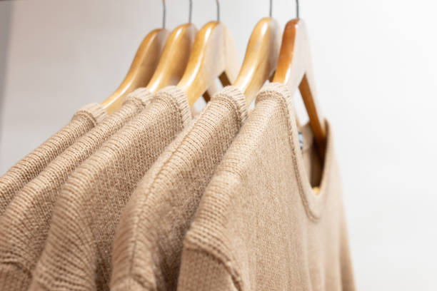 istock Warm woolen sweaters beige color hanging on hangers 1193362767