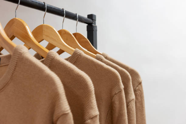 istock Warm woolen sweaters beige color hanging on hangers 1193362773