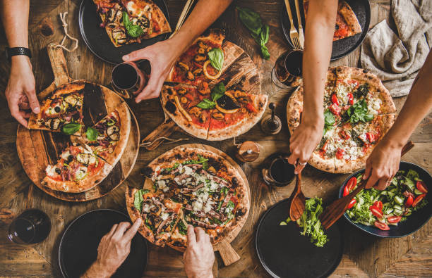 istock People cutting and eating pizza and drinking red wine 1193362940