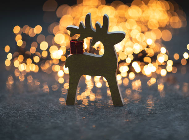 Christmas background Deer with a gift on the back and bokeh of lights.