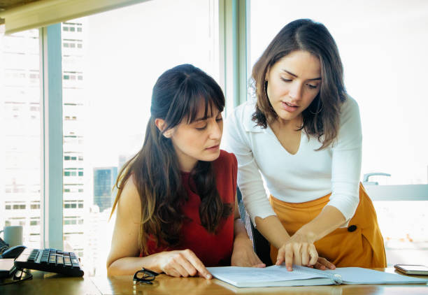 istock Professional female business assistant leans in to help her boss understand a point 1193364932