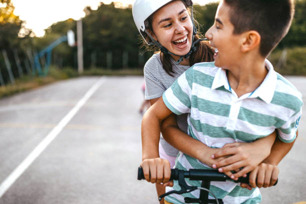 istock Brother and sister riding pushing scooter together 1193370179