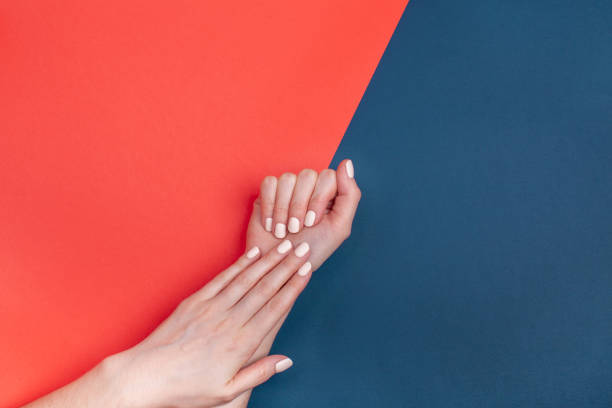 istock Beautiful female hands with a classic matte manicure on a blue-red background 1193373208