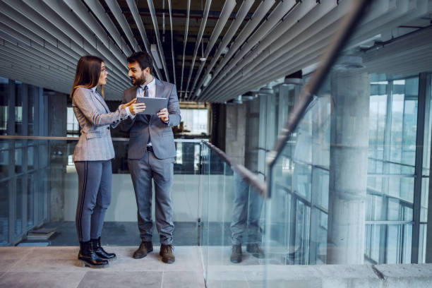 istock Two colleagues from successful corporate company standing in building in construction process and chatting. Man holding tablet. 1193380075