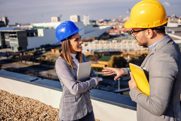 przystojny sprzedawca nieruchomości rozmawia z kobietą inwestora i przekonuje ją do zakupu budynku. stoją na szczycie budynku. - corporate business manager manual worker architect zdjęcia i obrazy z banku zdjęć