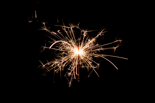 burning sparkler and flying sparks on a black background, festive sparkler