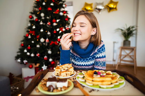 Beautiful Caucasian girl treating herself with a homemade Christmas sweets.