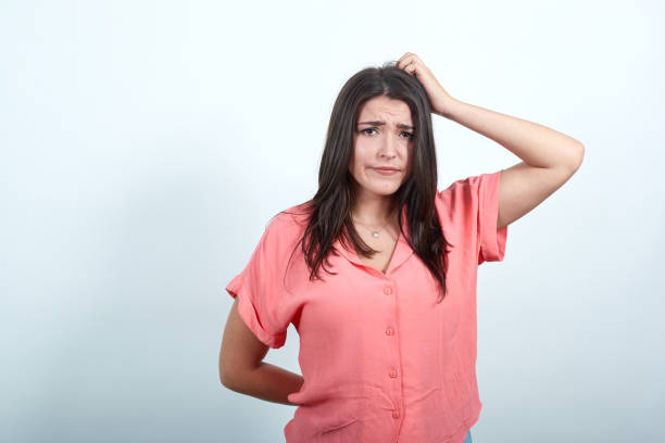 istock Woman keeping hand on head, holding hand behind back, looking dissatisfaction 1193388173