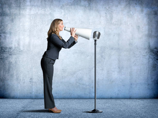 istock Businesswoman Using Megaphone To Speak Into A Microphone 1193392401
