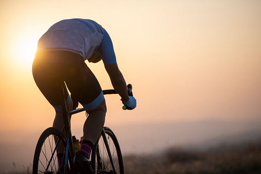Athlete on racing bike outdoors at sunset.