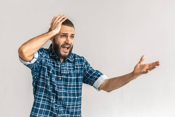 istock Freestyle. Guy in checkered shirt standing isolated on white holding head shouting gesturing concerned 1193399944