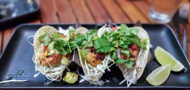 Fresh caught Mahi Mahi fish tacos with shredded cabbage, avocado, tomatillo salsa, vine-ripened tomatoes, and cilantro on corn tortillas and a side of lime in Maui