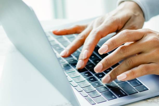 istock Dark skinned woman types on laptop, close up 1193404910