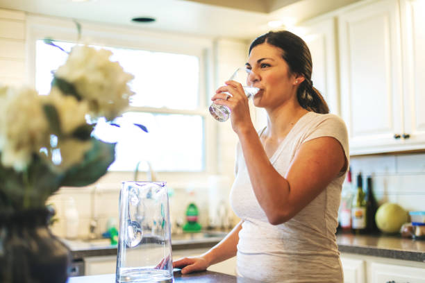 bella giovane adulta millennial femmina che usa l'acqua in casa residenziale - thirsty foto e immagini stock