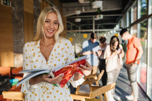 istock Blond girl holding a book while standing in a library 1193405870