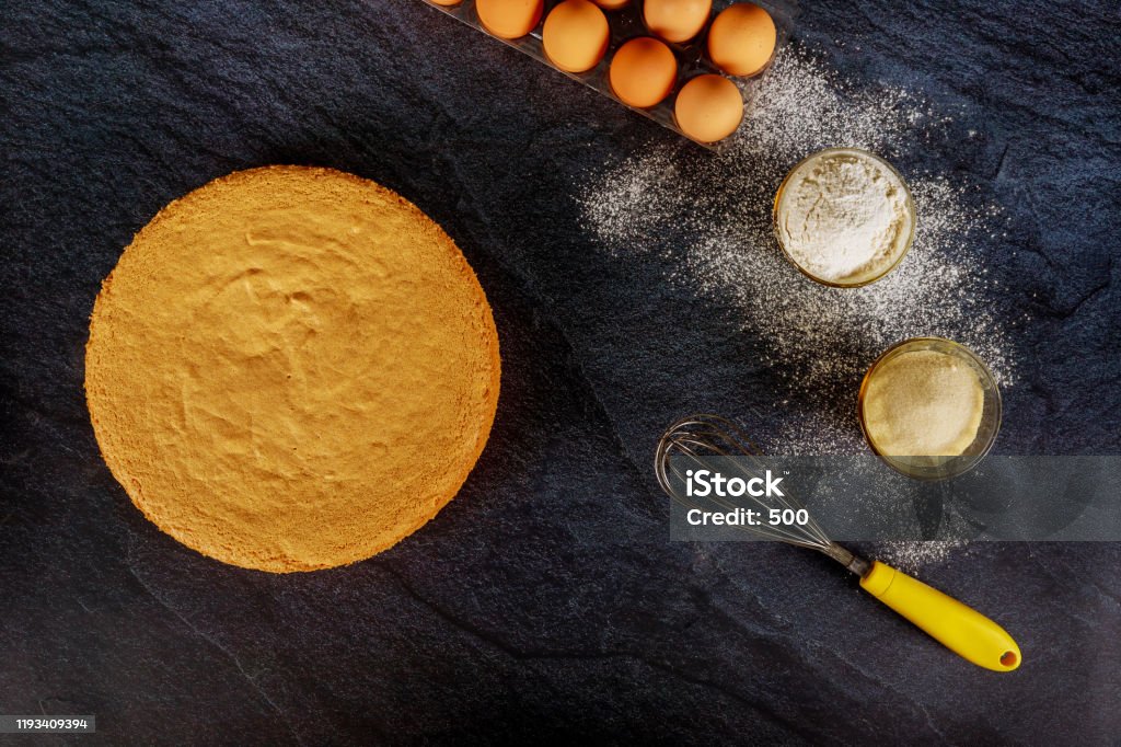 Sponge cake, biscuit on dark background with ingredients. Sponge cake, biscuit on dark background with eggs, flour and sugar. Vanilla Stock Photo