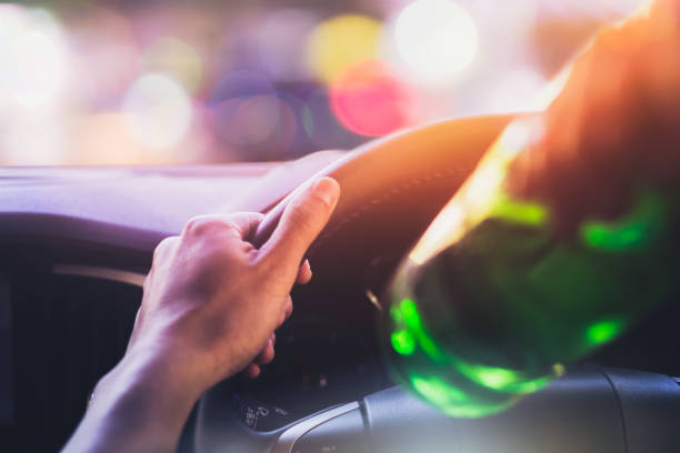 Drinking and driving ,man drinking alcohol while driving car after party at night time stock photo