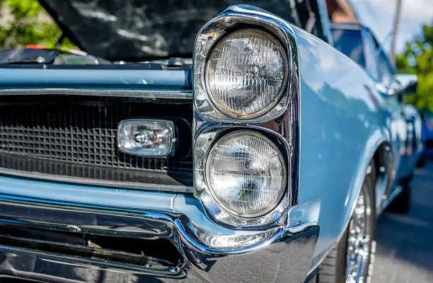Photo of Headlights of an old powerful muscular blue retro car with an open hood