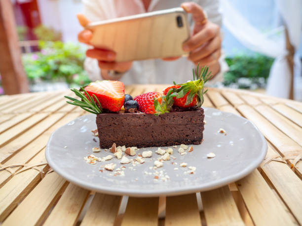 tarte au chocolat délicieuse sur le plat en céramique étant photographié avec le smartphone par la femme dans le café. - tart dessert chocolate fruit photos et images de collection