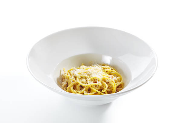 Italian Spaghetti Alla Carbonara with Grated Parmesan Italian spaghetti alla carbonara with grated parmesan, hard pecorino romano cheese, fried bacon, guanciale or pancetta, egg sause and black pepper on white restaurant plate isolated side view pecorino romano stock pictures, royalty-free photos & images