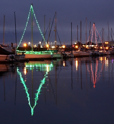 Two sailboats in the harbor decorated with Christmas lights