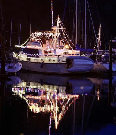 A small yacht decorated with reflecting Christmas lights